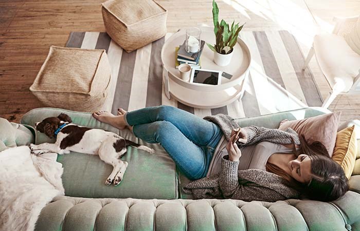 Kvinna och hund slappar i soffan